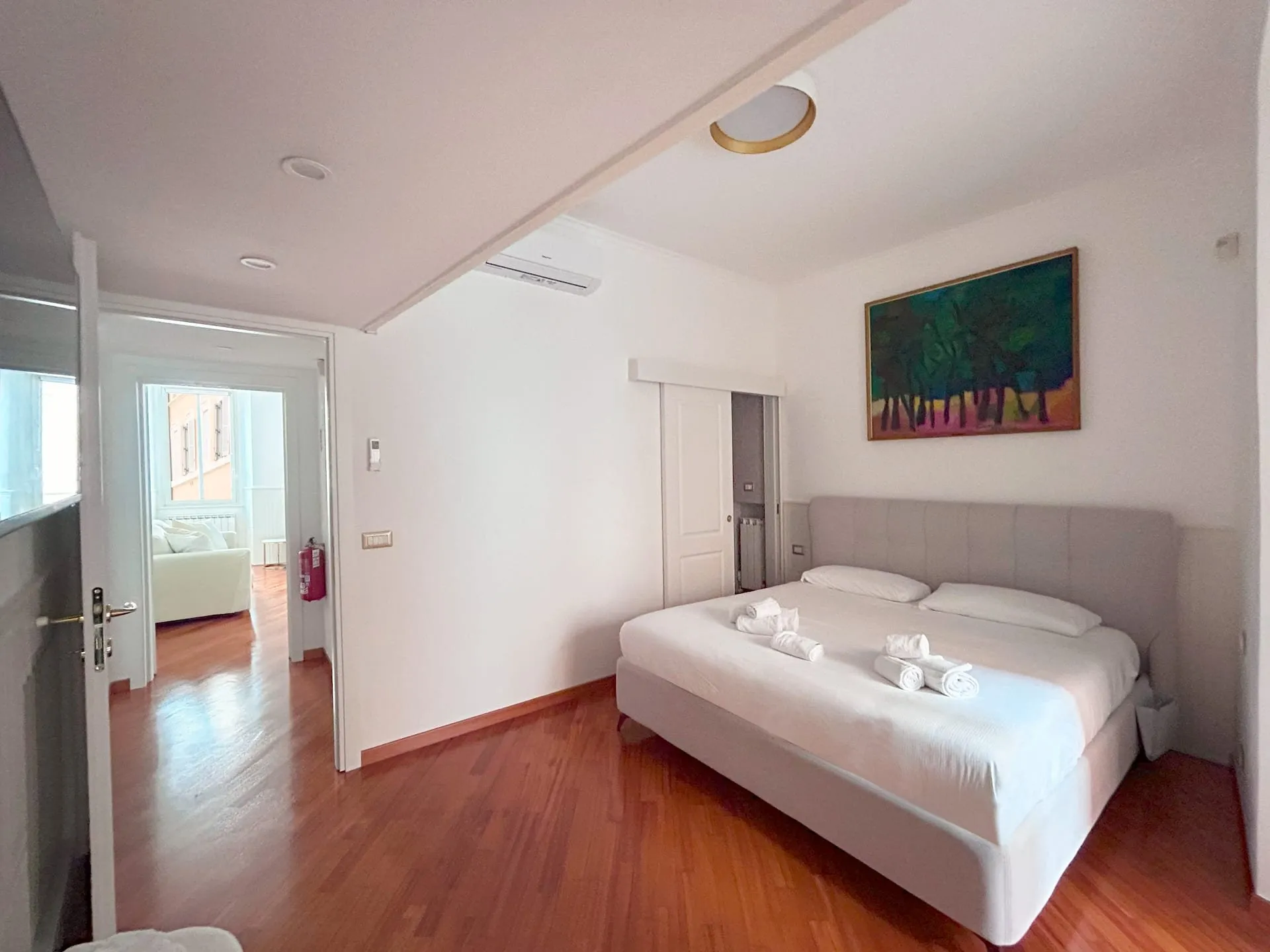 Camera vista dalla porta, con il letto matrimoniale e un quadro di alberi