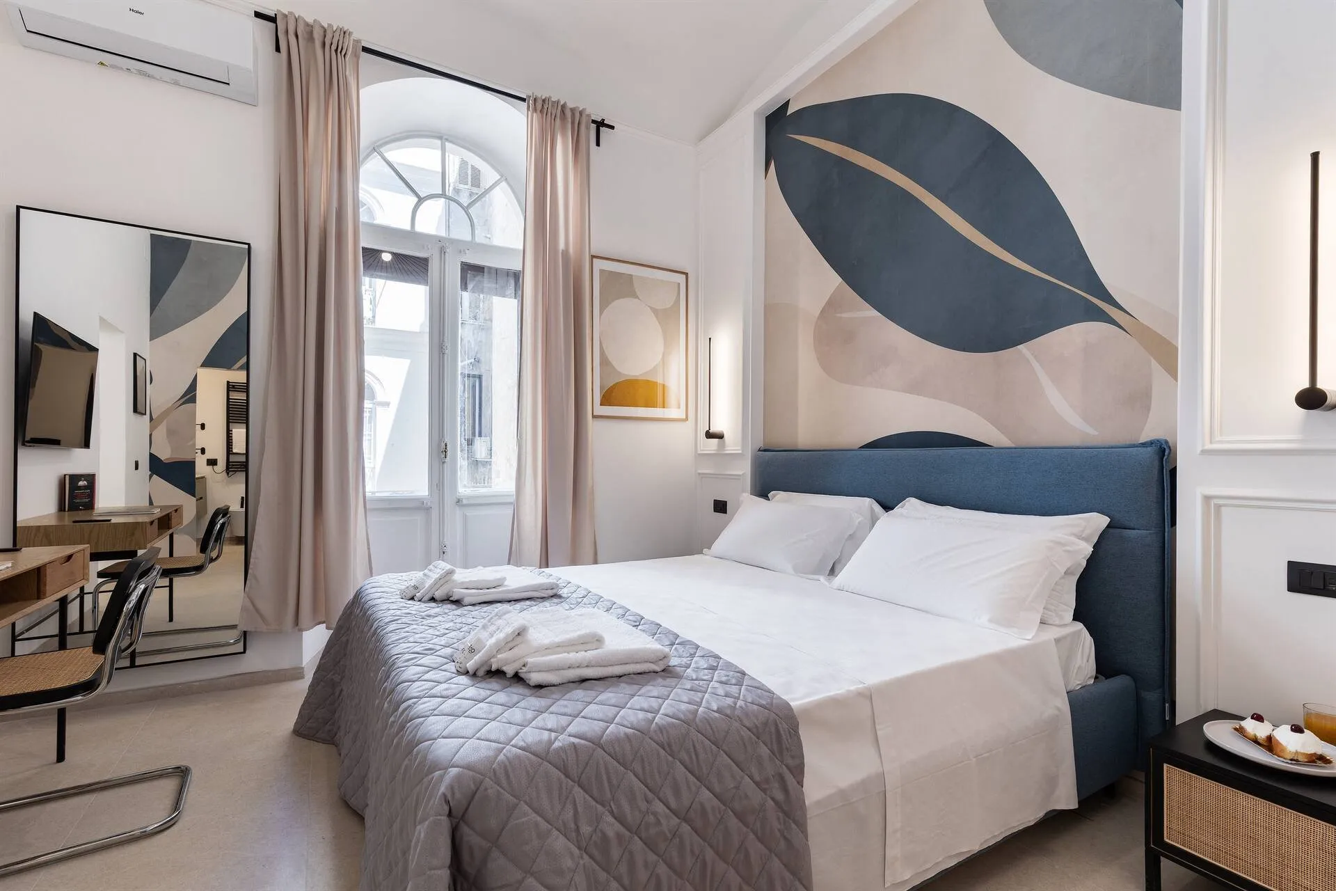 Camera con letto matrimoniale e scrivania, davanti alla porta finestra ad arco