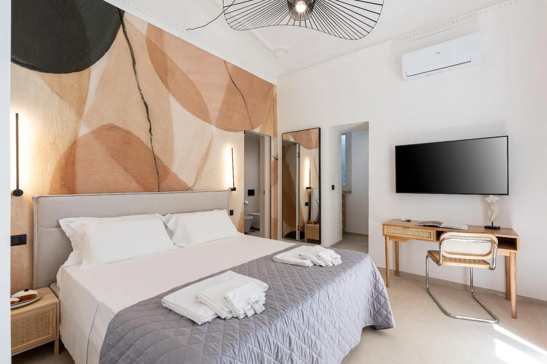 Camera con letto matrimoniale, scrivania e televisore alla parete