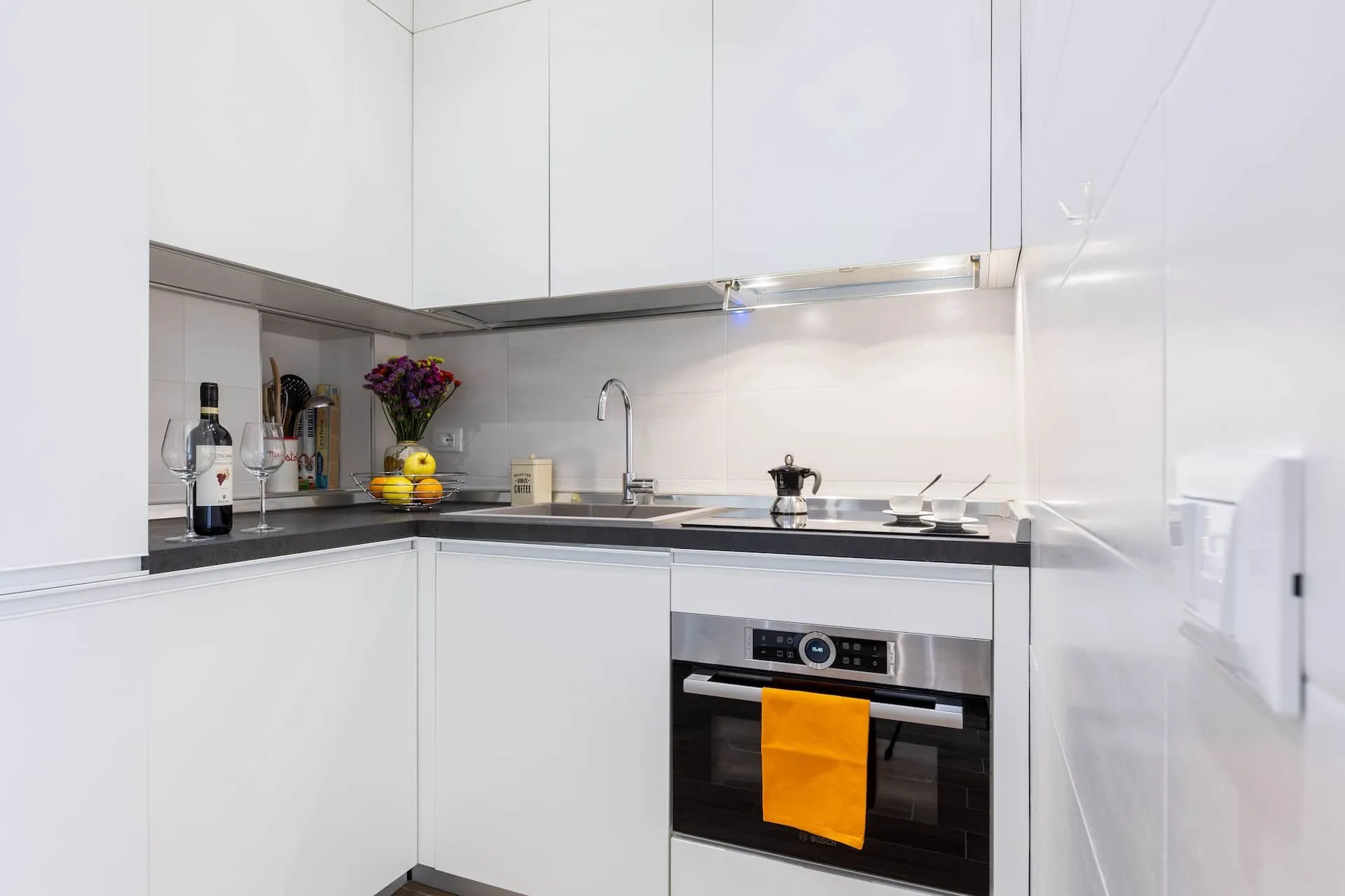 Cucina bianca ad angolo con forno e piano grigio