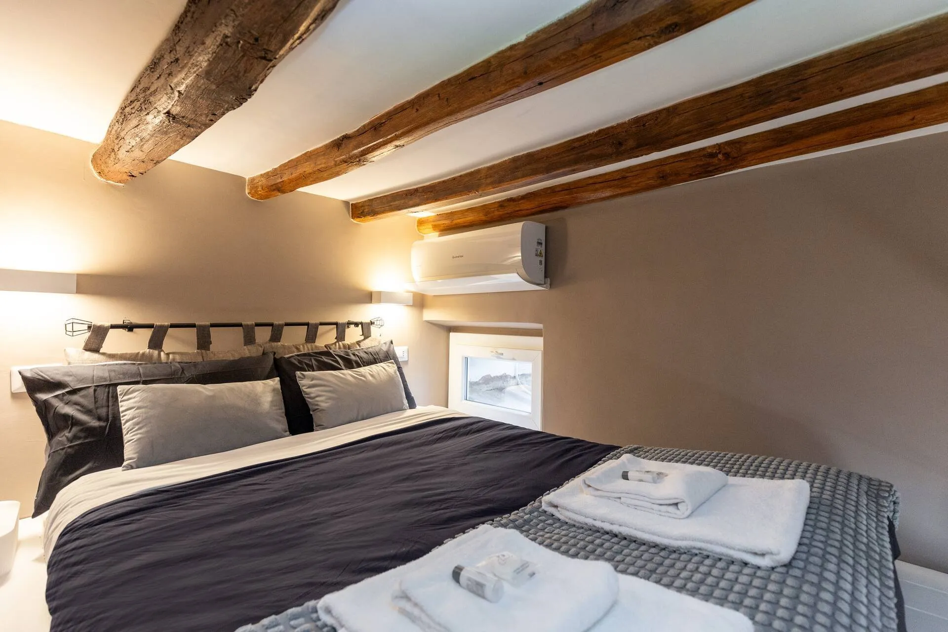 Camera sul soppalco con letto matrimoniale e travi di legno a vista
