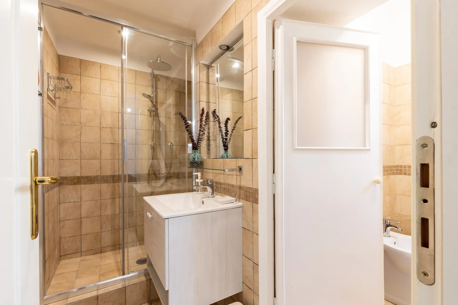 Bagno con doccia in vetro, piastrelle beige e mobile bianco