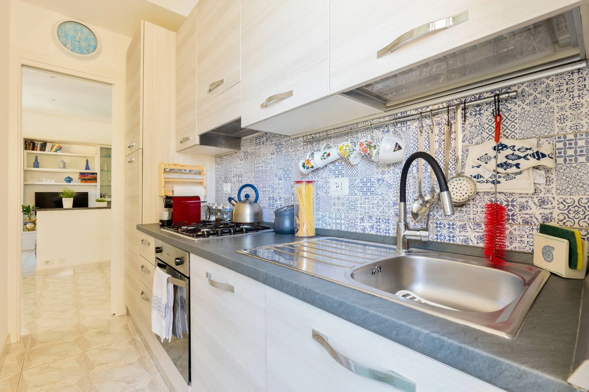 Cucina con piastrelle decorate blu e bianche, piano grigio e fornelli a gas