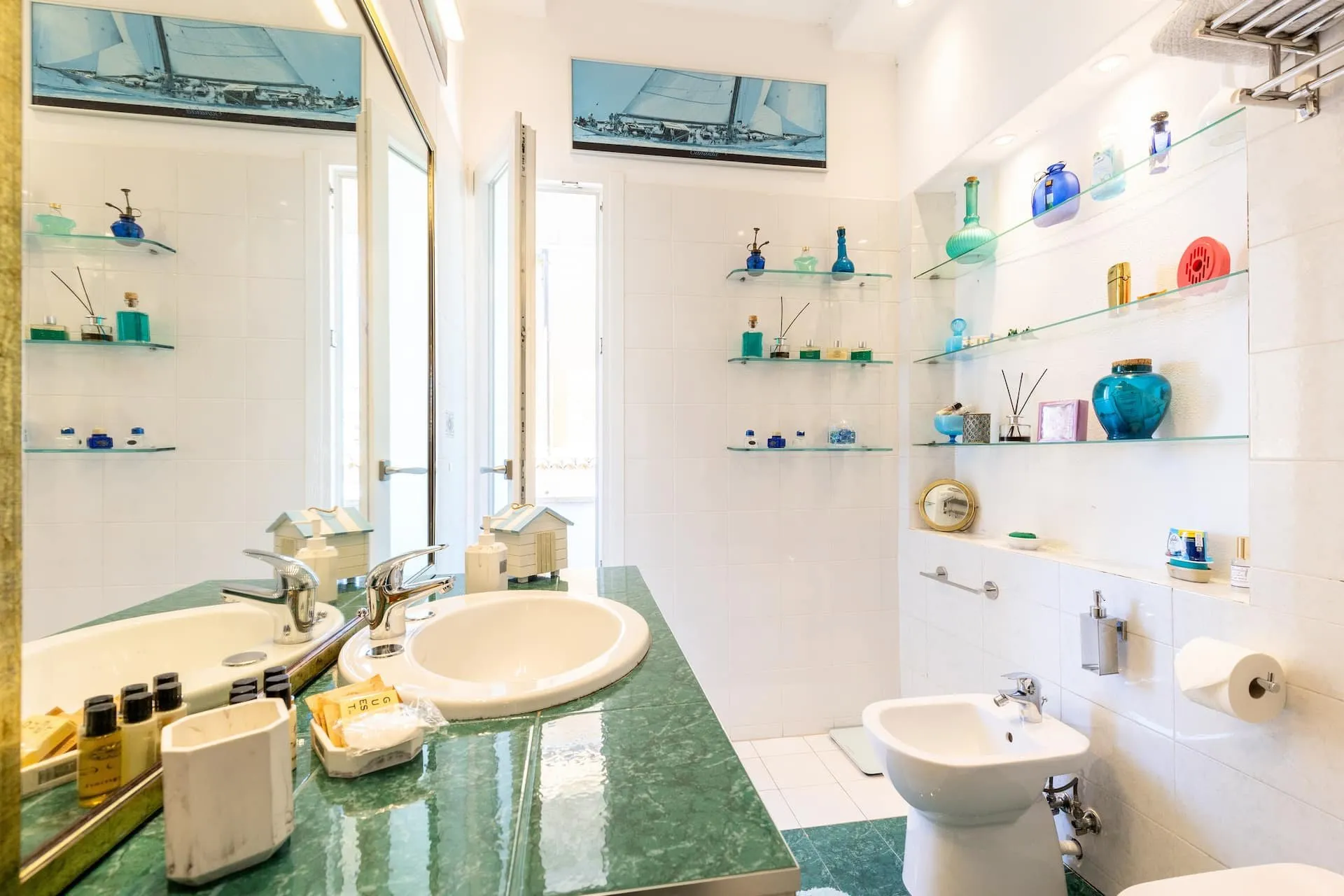Bagno con piano verde, lavabo bianco e mensole di vetro