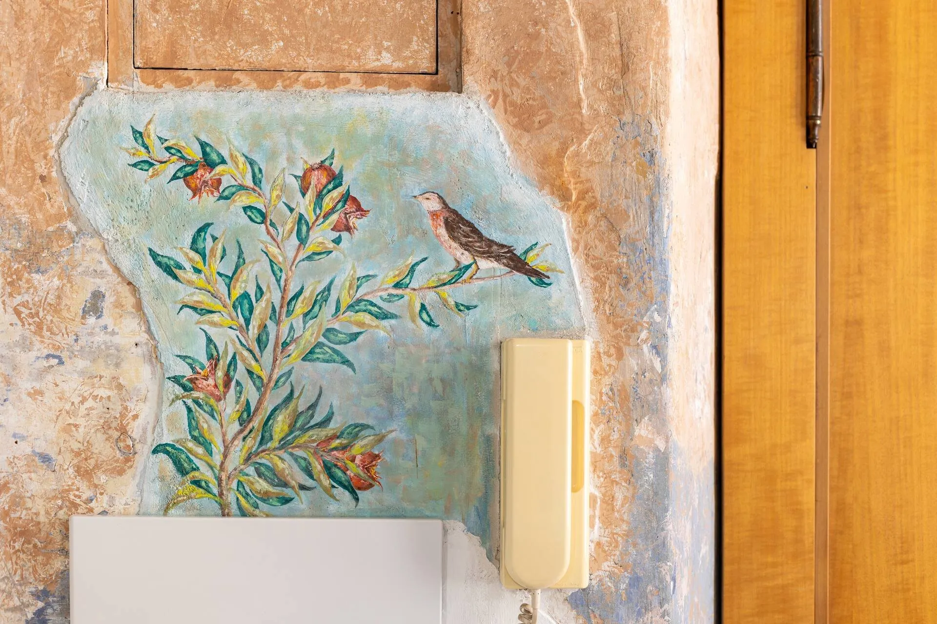 Frammento di affresco con un ramo fiorito e un uccellino, conservato nel muro accanto alla porta