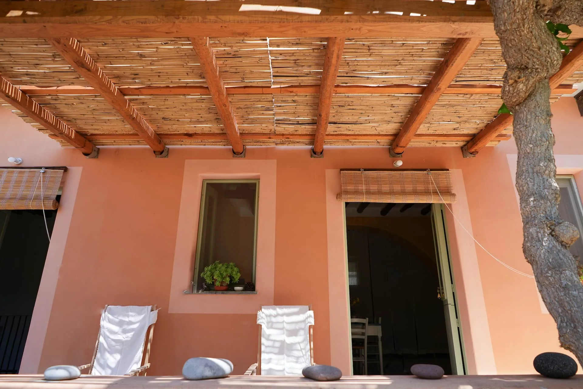 Veranda sotto il pergolato di canne, con due sedie a sdraio davanti alla casa