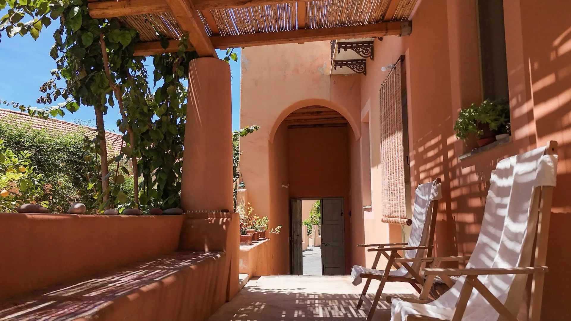 Portico color terracotta con sedie a sdraio e una porta ad arco sul fondo