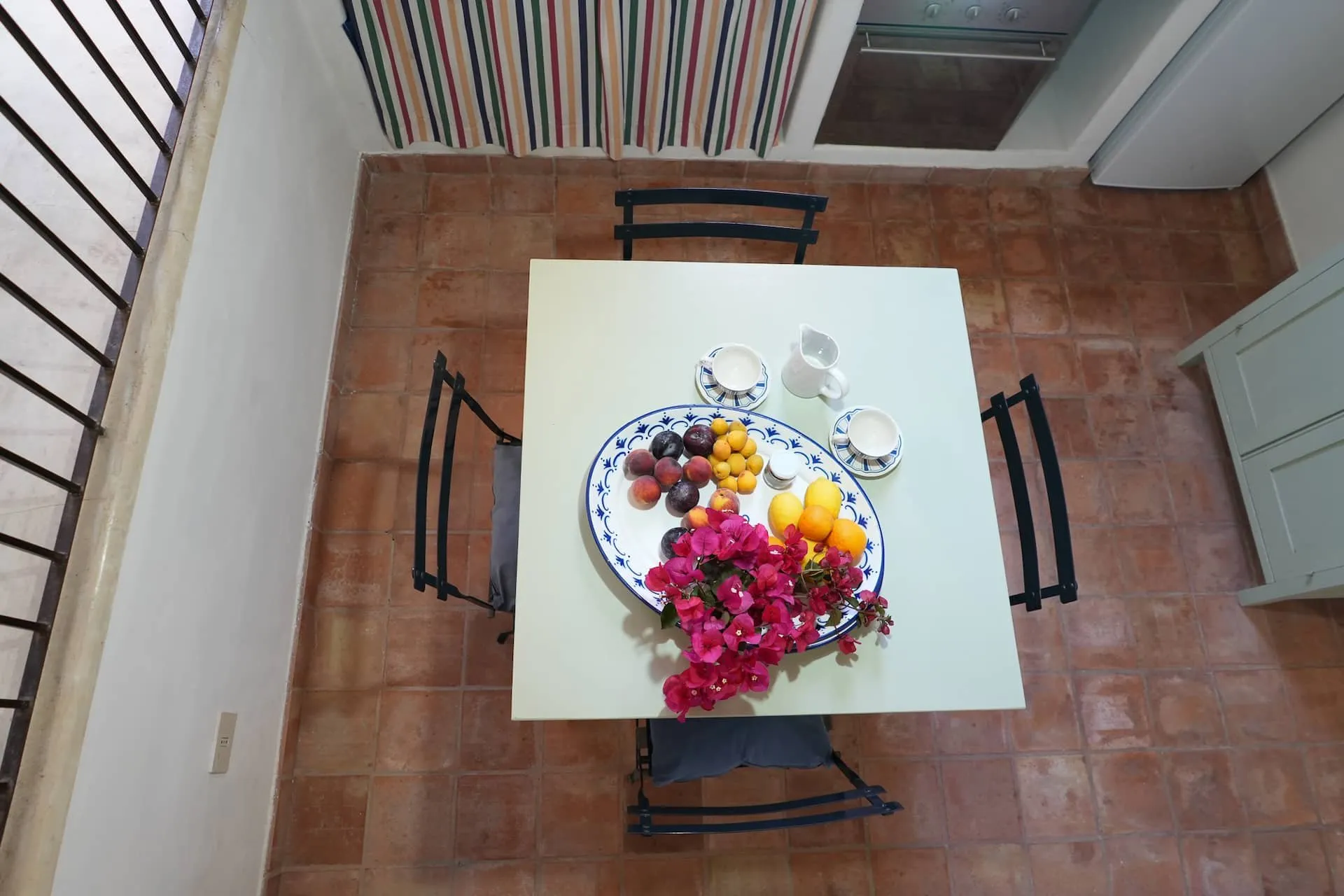 Tavolo bianco con frutta visto dall'alto, pavimento di cotto