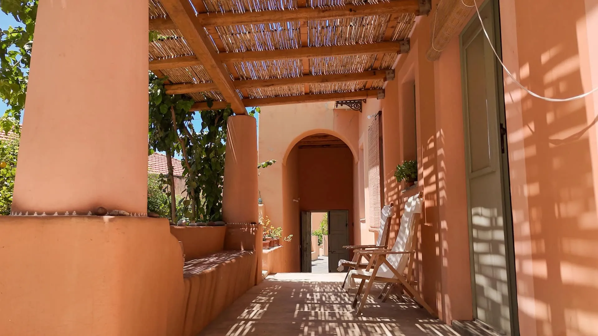 Portico intonacato color terracotta con la tettoia di canne