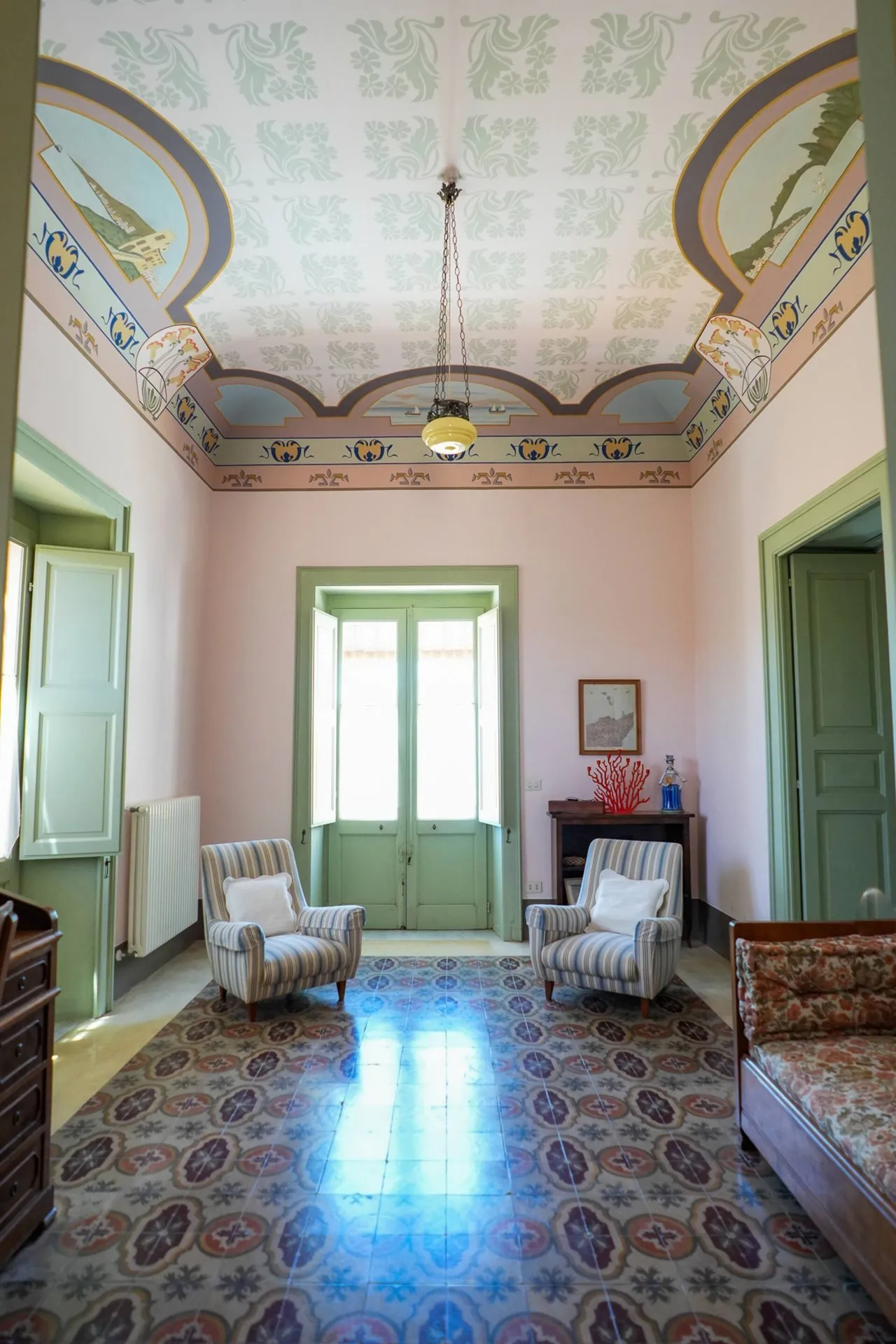 Salotto con soffitto dipinto, pavimento di graniglia e porta finestra verde
