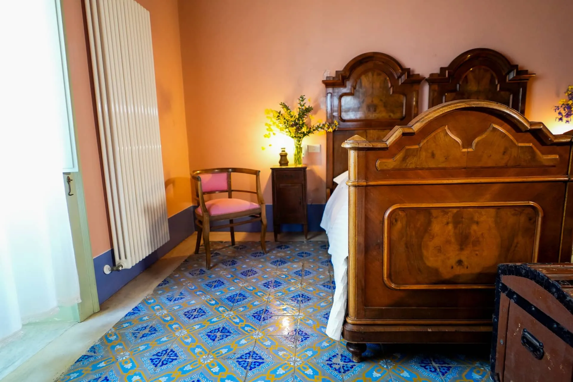 Camera con letto antico in legno intarsiato e pavimento di maioliche azzurre
