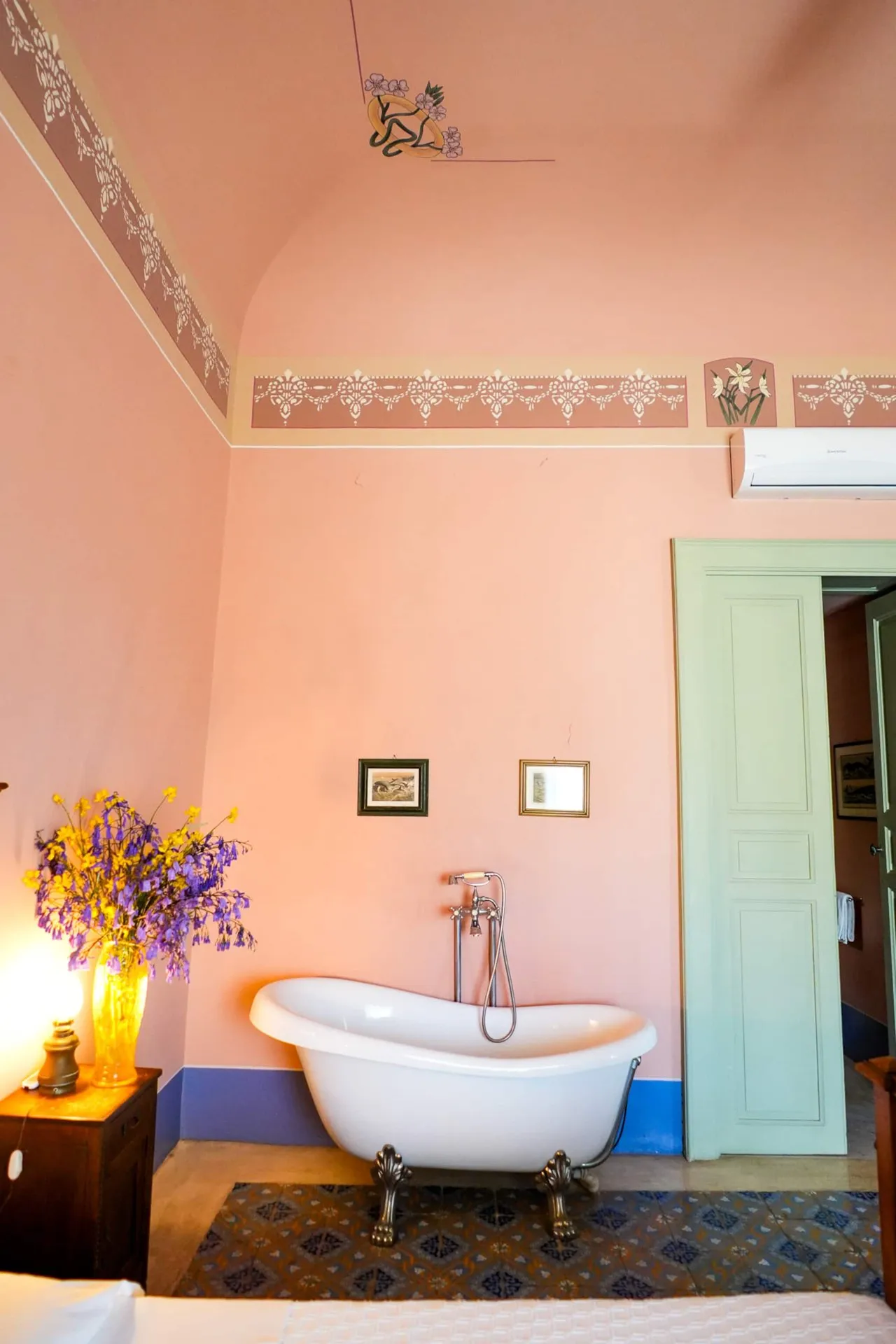 Bagno rosa con vasca su piedini e porta azzurra