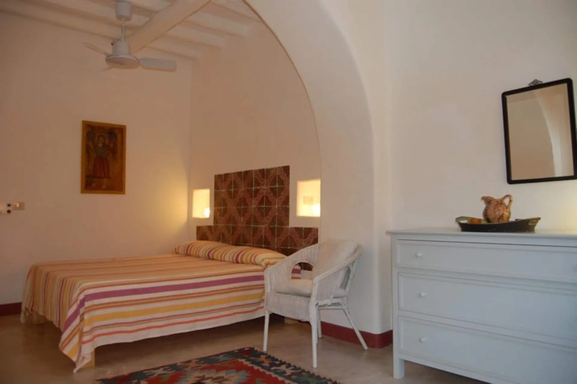 Camera con letto matrimoniale, copriletto a righe e comò bianco