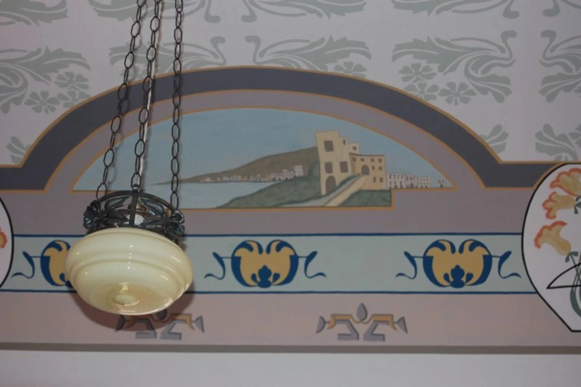 Fregio dipinto sul soffitto con un paesaggio di mare e una lampada a sospensione