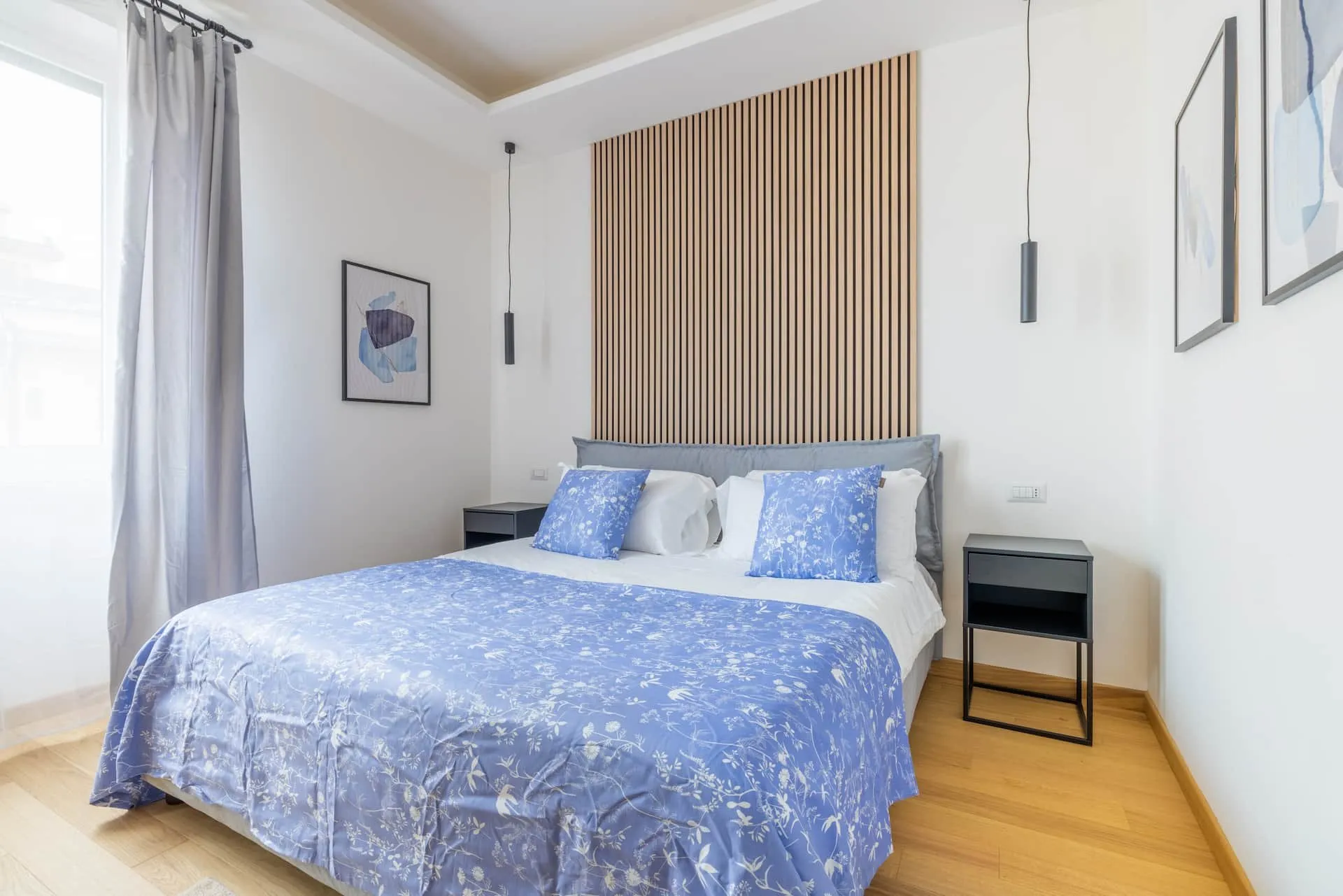 Letto matrimoniale con coperta azzurra dietro un divisorio di legno