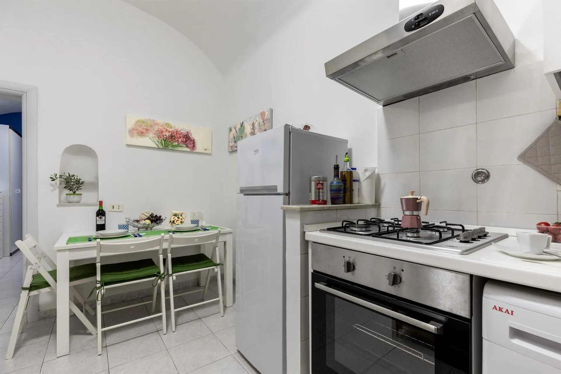 Cucina bianca con forno e frigorifero, tavolo con tovagliette verdi