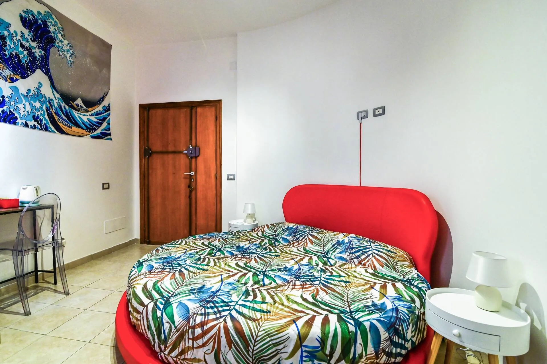 Letto rotondo e porta d'ingresso in legno, con una stampa dell'onda giapponese alla parete