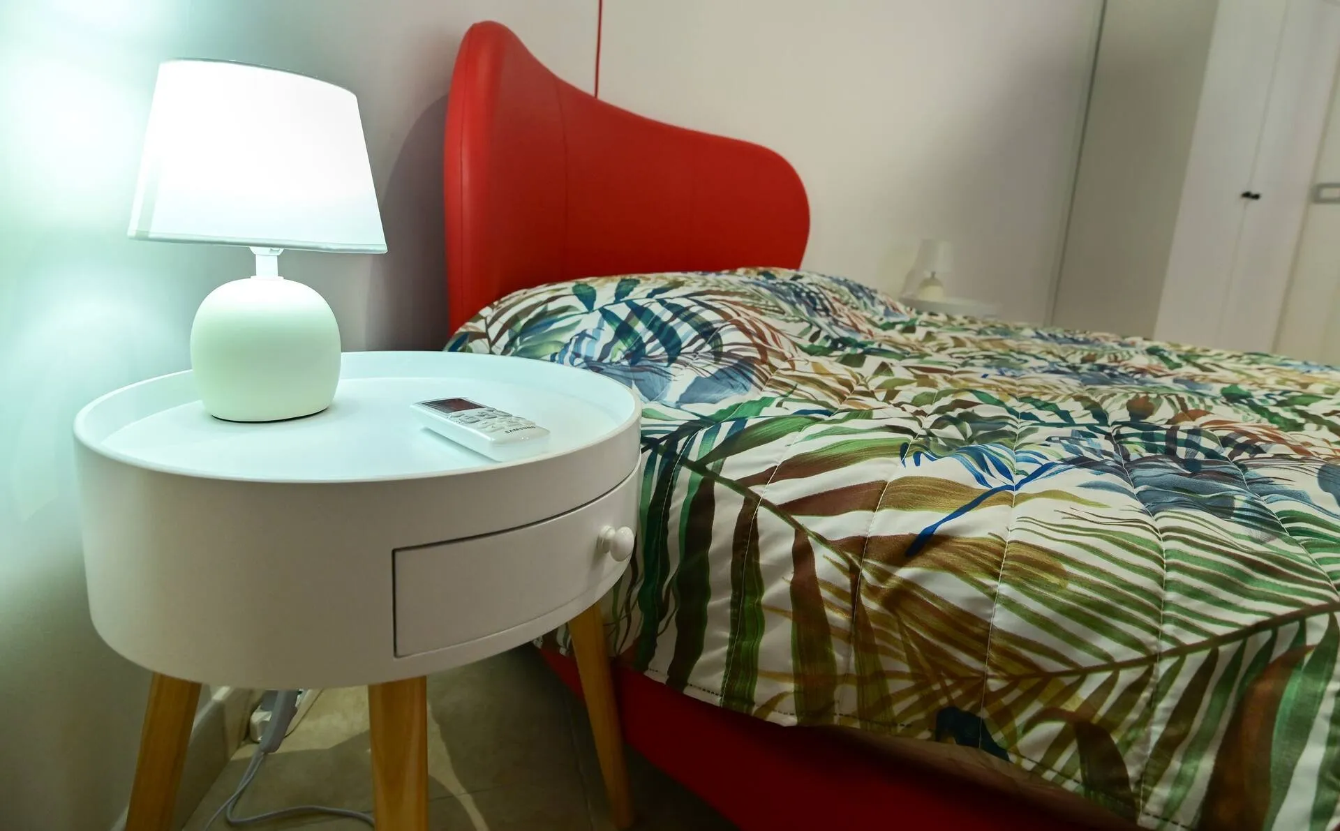 Comodino bianco con lampada accanto al letto