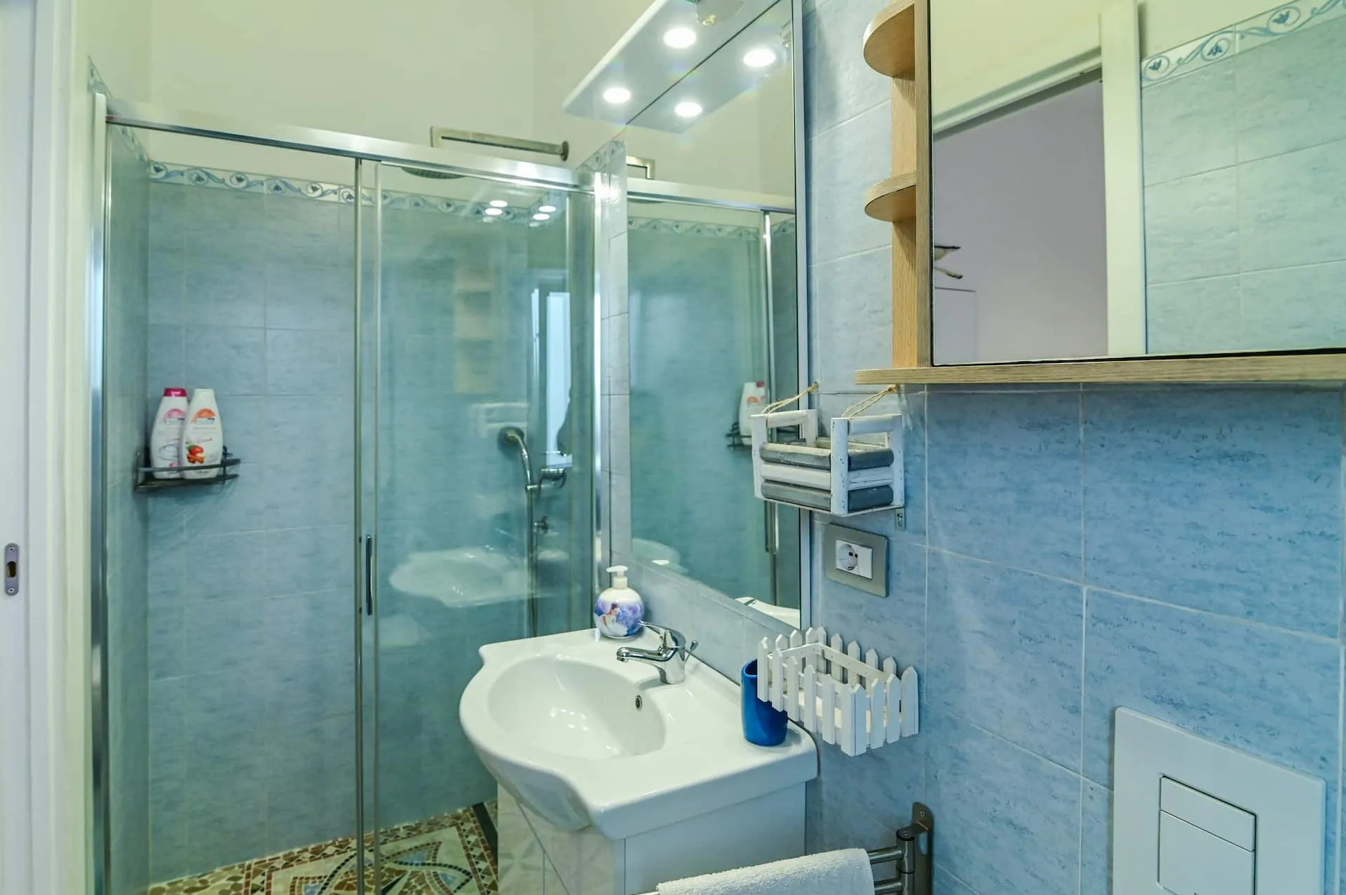 Bagno privato azzurro con doccia in vetro e lavabo