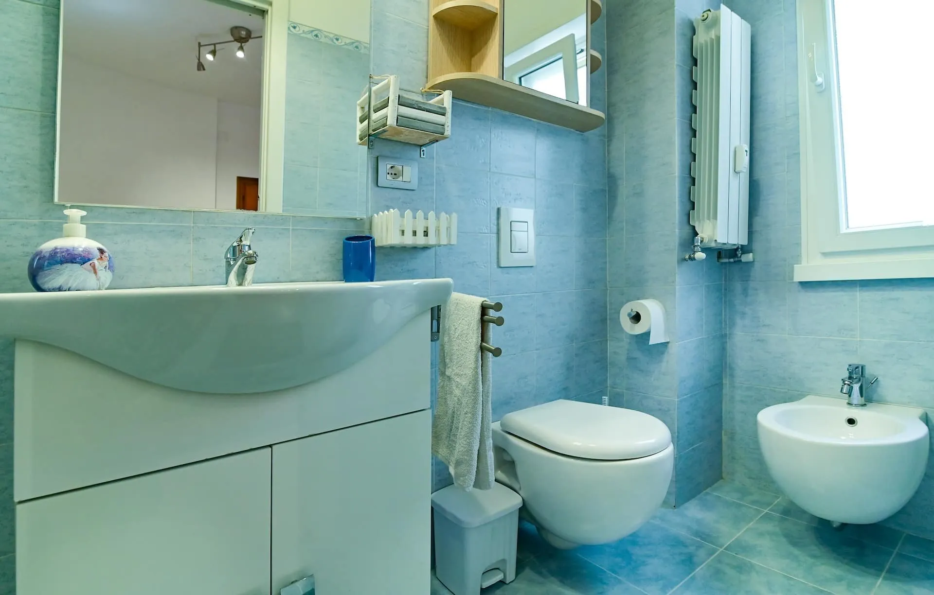 Bagno con sanitari sospesi e lavabo bianco, finestra sulla destra