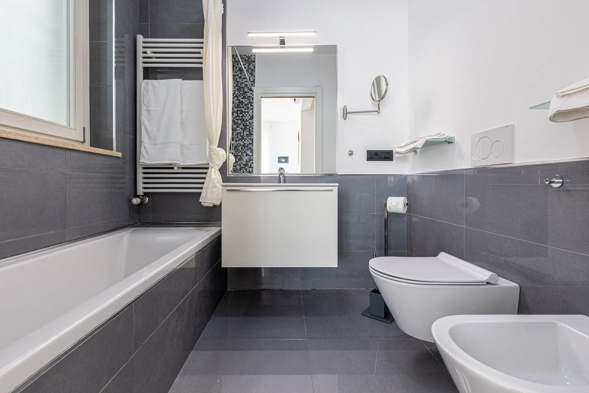 Bagno grigio e bianco con vasca e finestra