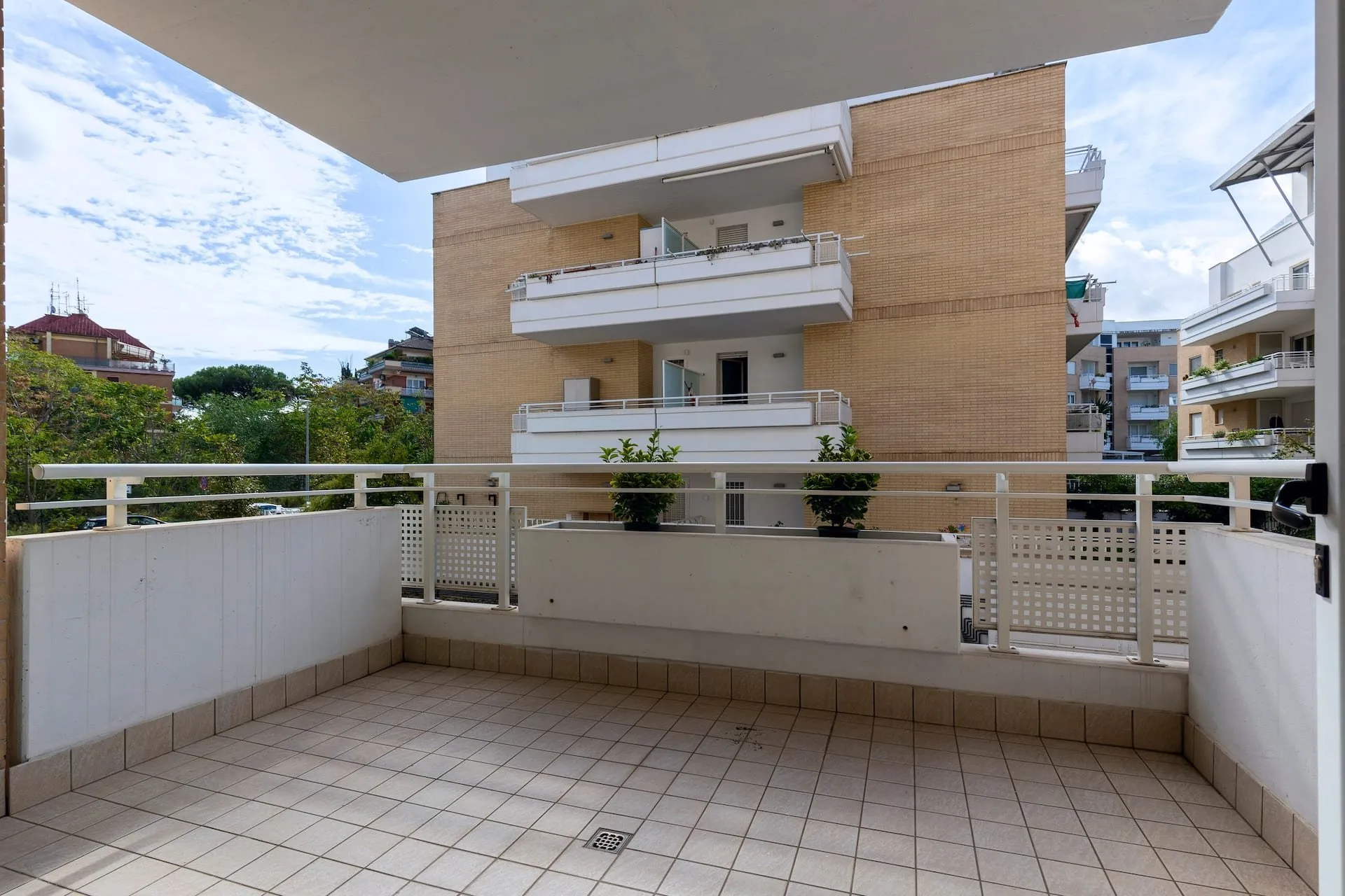Balcone ampio con la ringhiera bianca, affacciato sui palazzi e sugli alberi