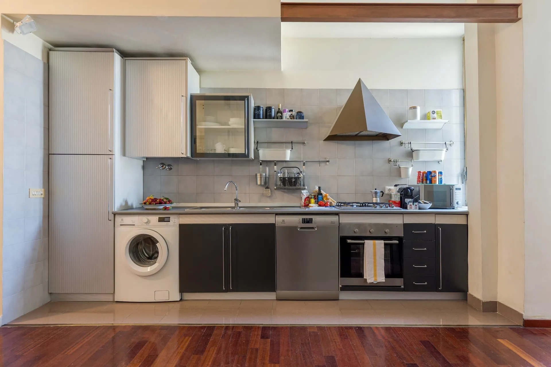 Cucina lineare con lavatrice, lavastoviglie, forno e cappa d'acciaio